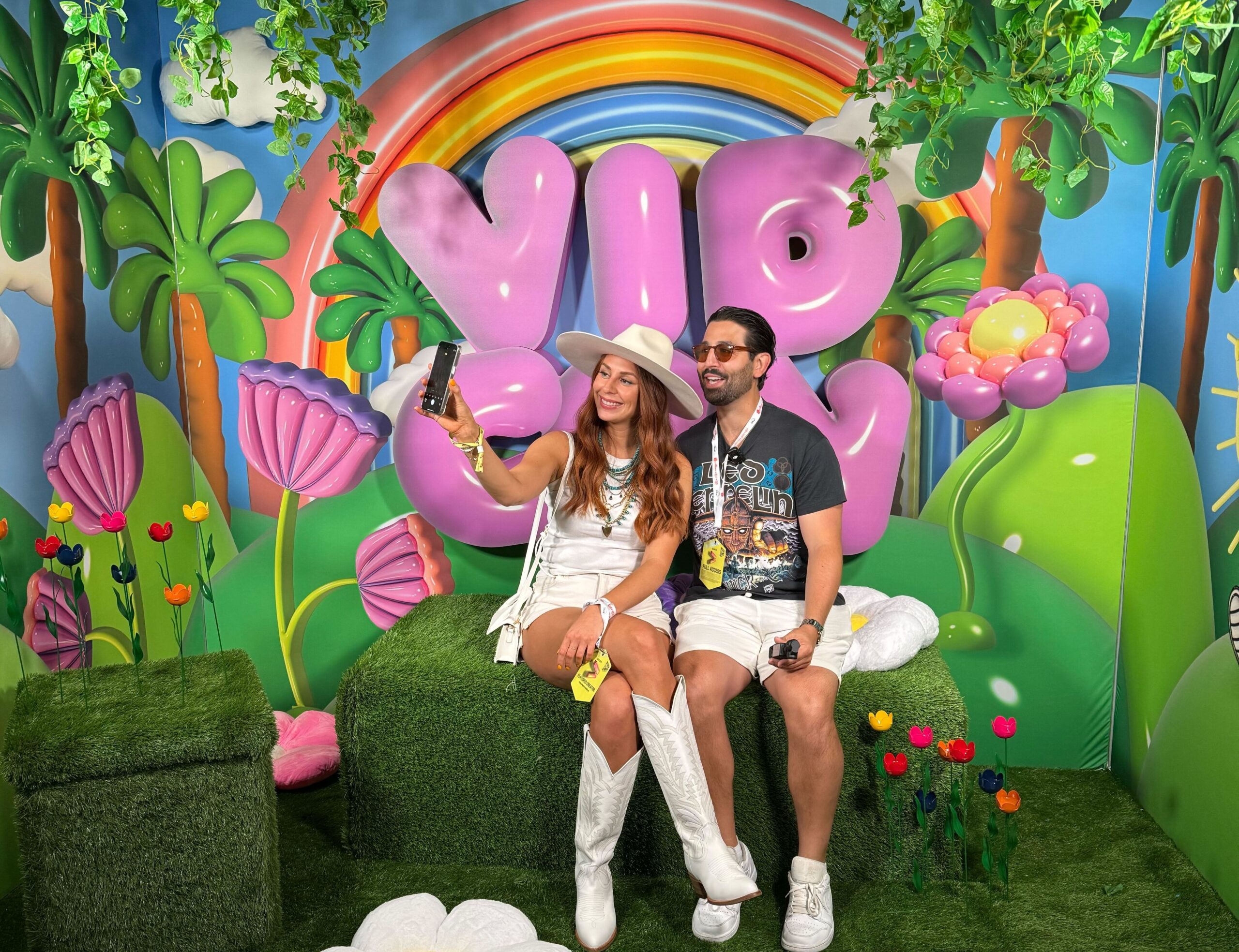 Creators taking a selfie in front of a tropical VidCon scene. 